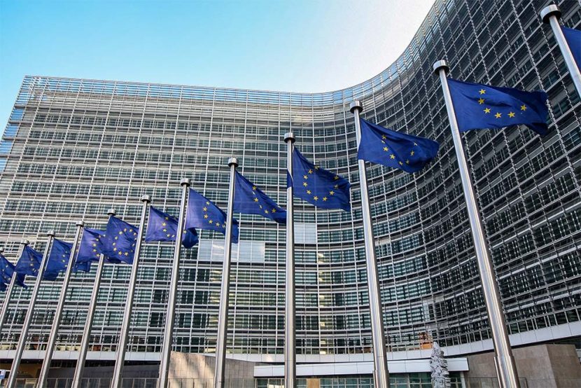 Several European Union flags fly in front of a building.